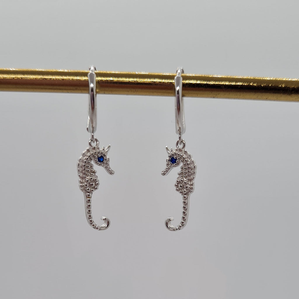 Silver seahorse huggie hoop earrings. Blue gem on seahorse's eye
