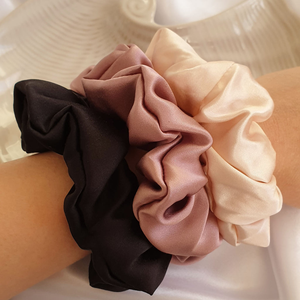 1 mauve pink, 1 pink and 1 black big silk scrunchie on model's arm