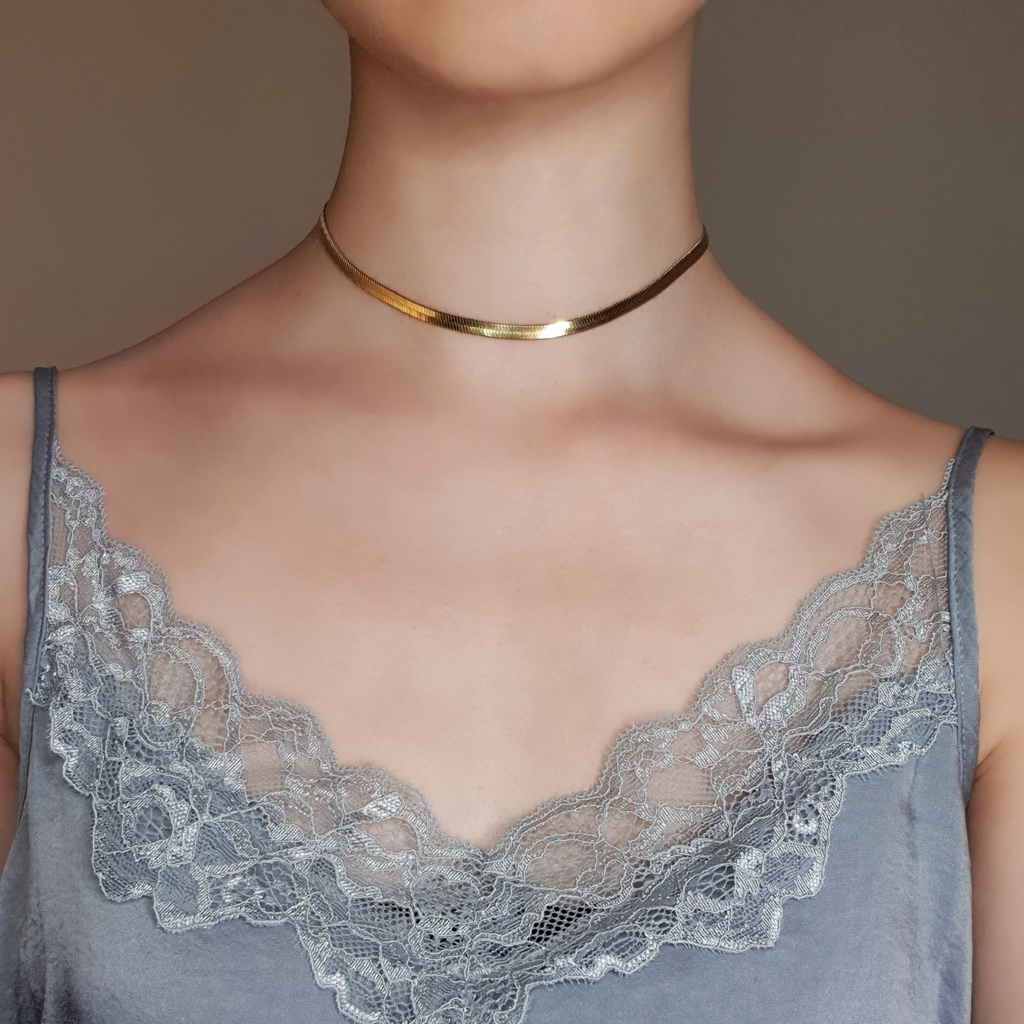 Gold flat lay snake necklace on model wearing silver lace top