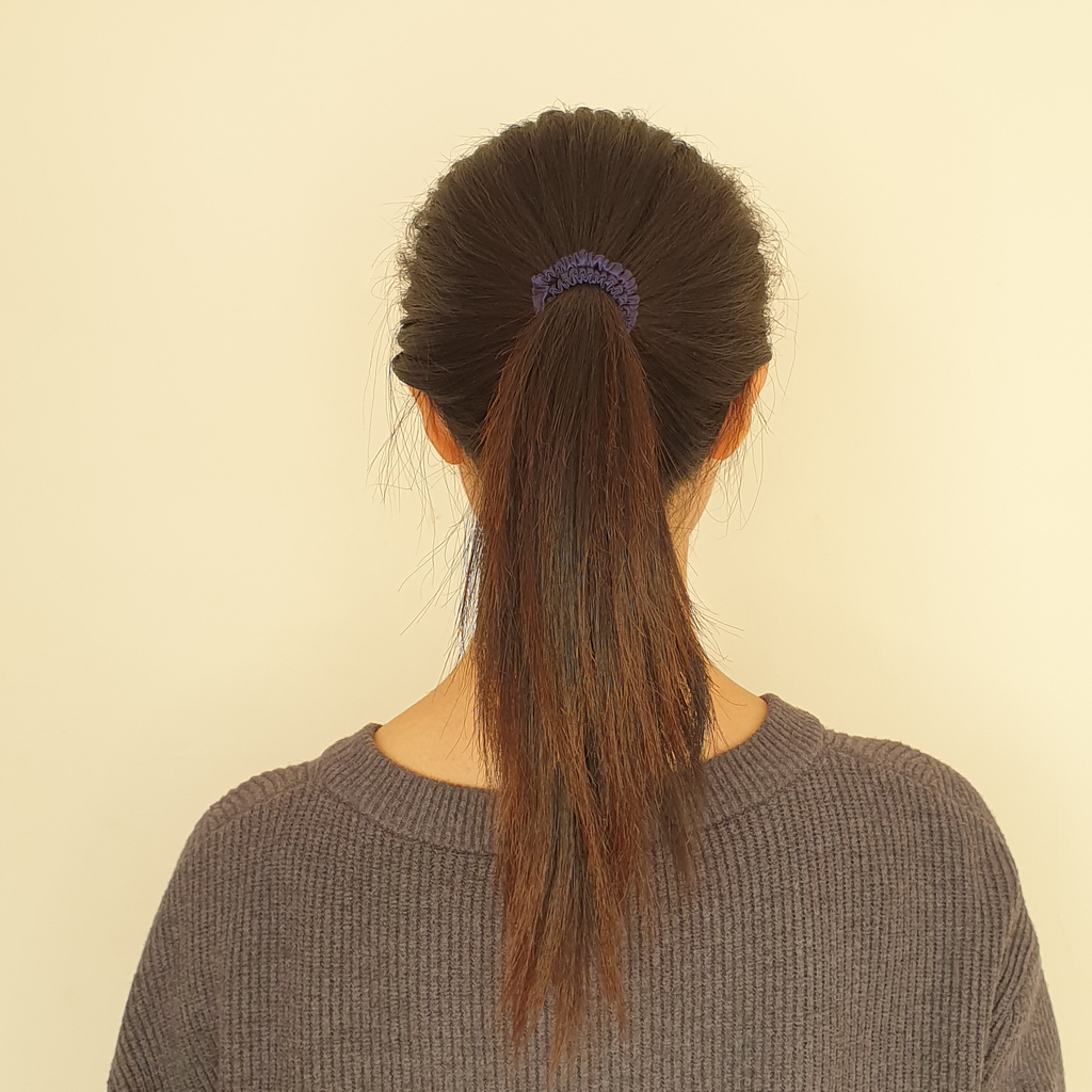 Navy blue slim silk scrunchie in model's hair