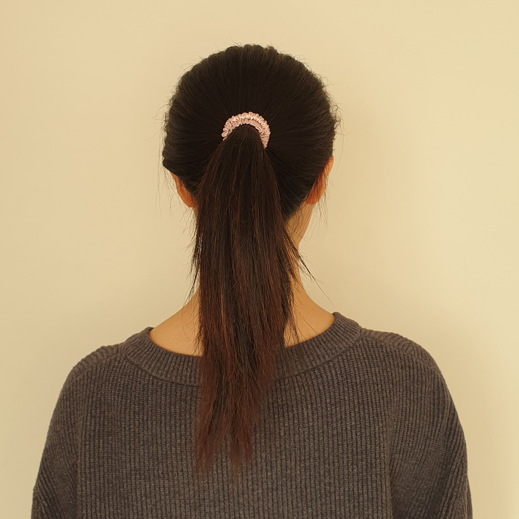 Model wearing pink coloured slim silk scrunchie in hair